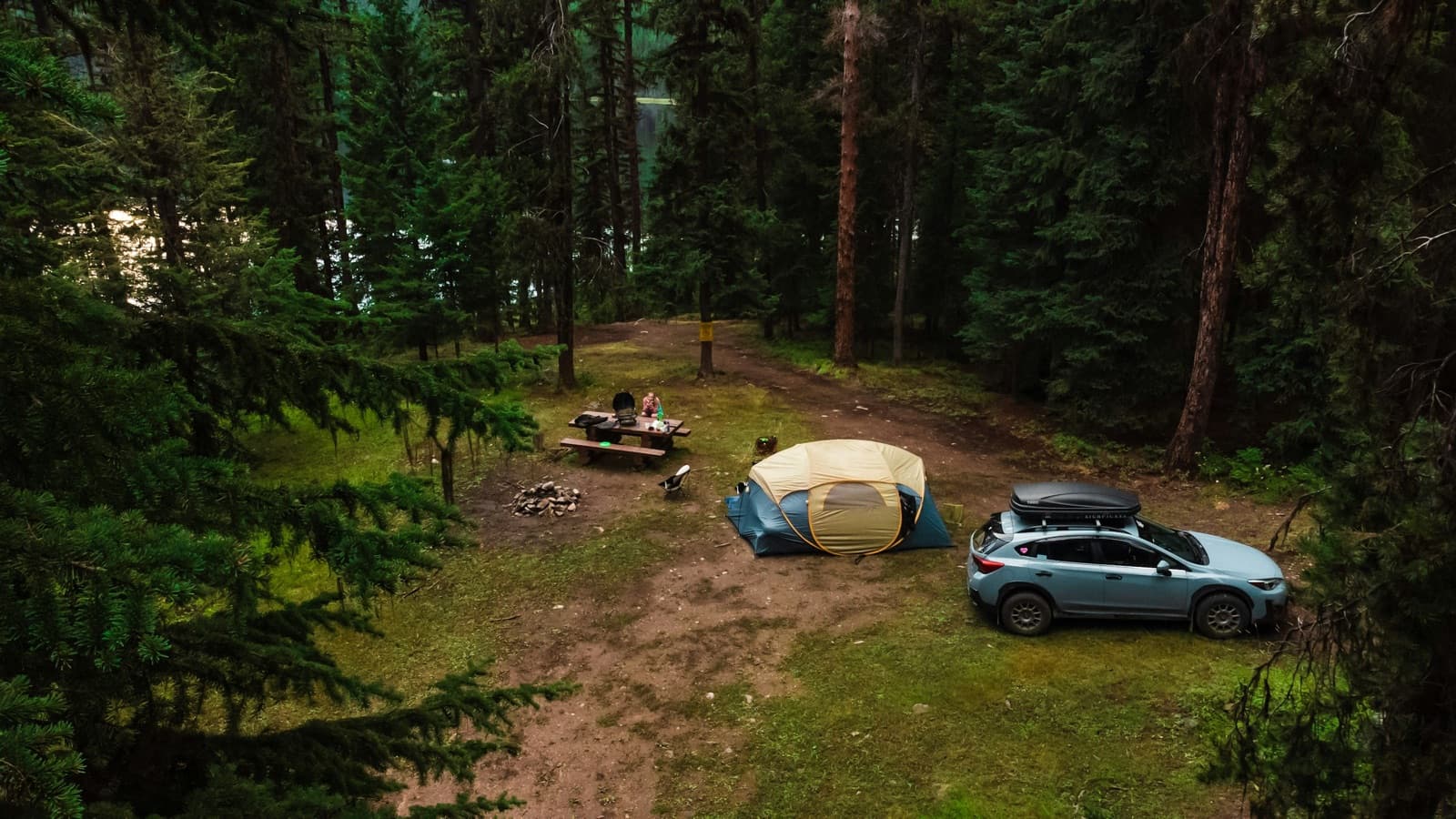 A vehicle parked next to a rooftop tent in the woods, BC, Canada
