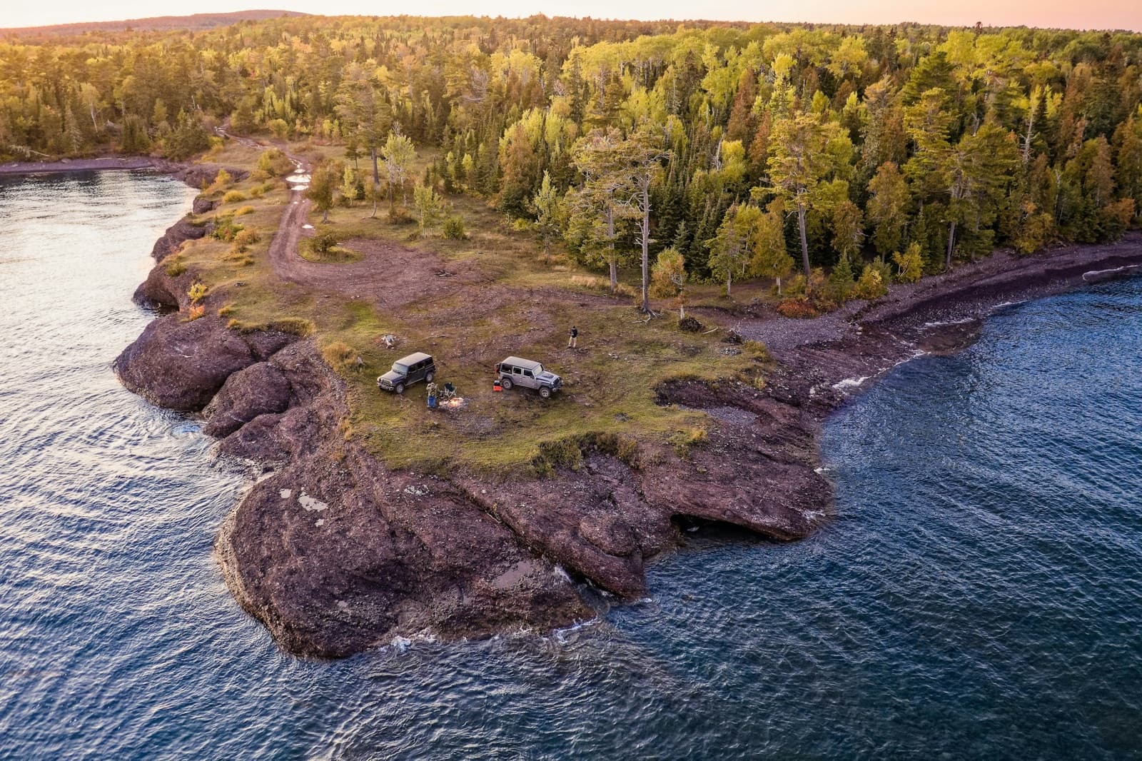 Two vehicles on a cliff facing the ocean